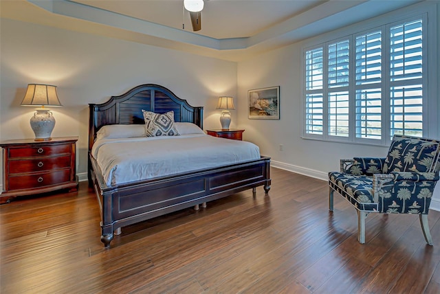 bedroom featuring a raised ceiling, ceiling fan, and dark hardwood / wood-style flooring