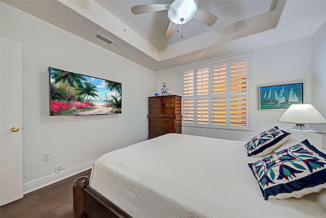 bedroom featuring dark hardwood / wood-style flooring, a raised ceiling, and ceiling fan