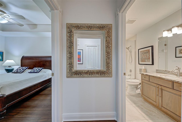 bedroom with hardwood / wood-style floors, ceiling fan, sink, and ensuite bath