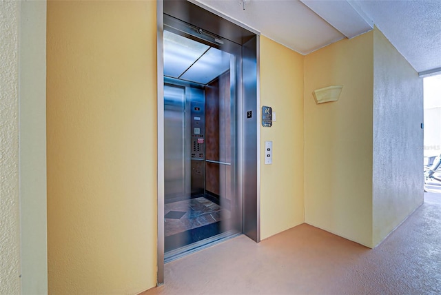 corridor featuring elevator and light colored carpet