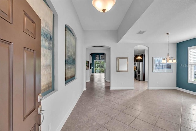 tiled entryway with a notable chandelier