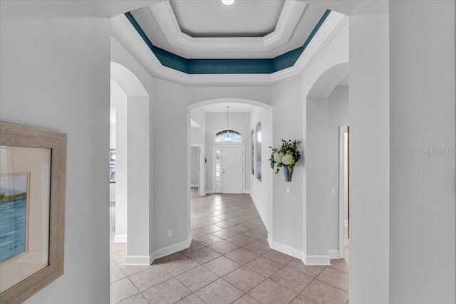 hallway with a raised ceiling, plenty of natural light, and light tile patterned floors