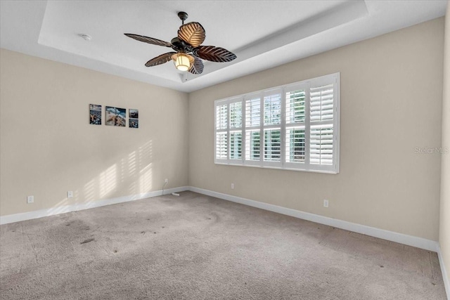 carpeted spare room featuring a raised ceiling and ceiling fan