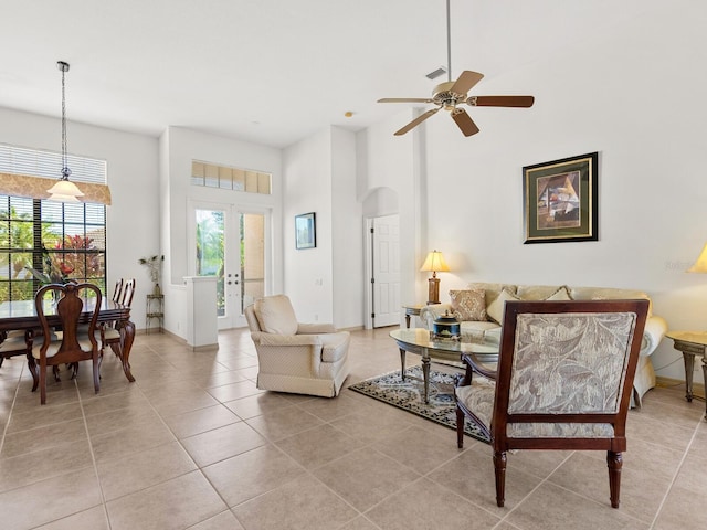 living room with ceiling fan, light tile patterned floors, a high ceiling, and french doors