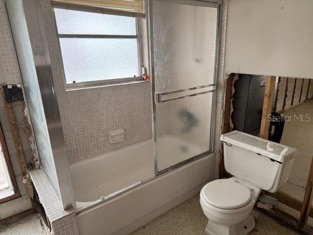 bathroom featuring combined bath / shower with glass door and toilet