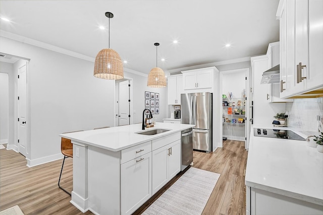 kitchen featuring light wood-type flooring, stainless steel appliances, sink, a center island with sink, and white cabinets