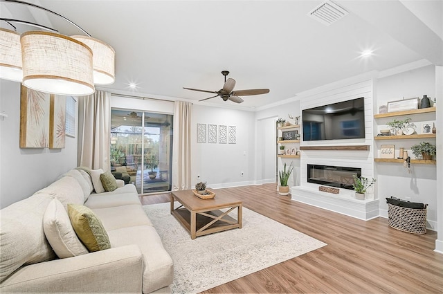 living room with a fireplace, ceiling fan, hardwood / wood-style floors, and crown molding