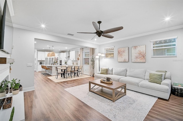 living room with ceiling fan, light wood-type flooring, and ornamental molding