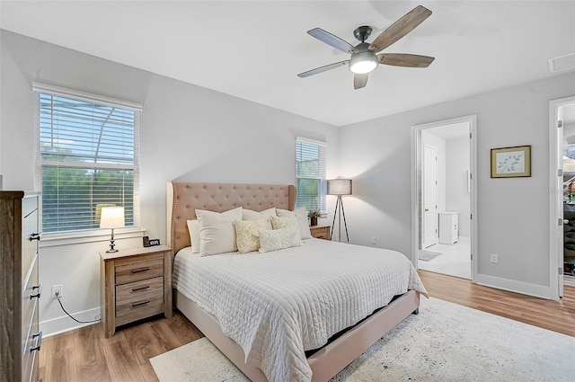 bedroom with light wood-type flooring, ceiling fan, and connected bathroom