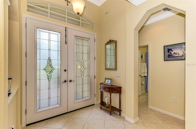 entryway with light tile patterned floors, crown molding, and french doors