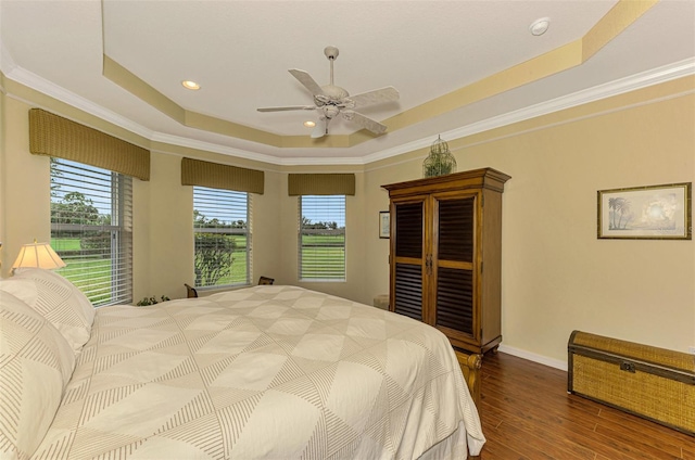 bedroom with a raised ceiling, multiple windows, ceiling fan, and ornamental molding