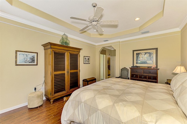 bedroom featuring a tray ceiling, crown molding, ceiling fan, and wood-type flooring