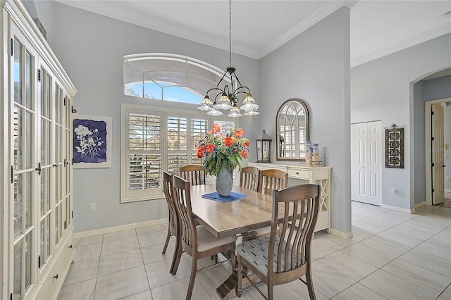 tiled dining area featuring a high ceiling, crown molding, and a notable chandelier