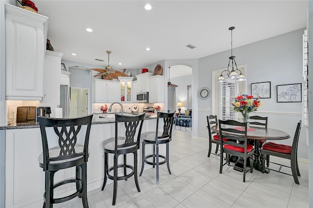 kitchen featuring pendant lighting, light tile patterned floors, dark stone countertops, a chandelier, and white cabinetry