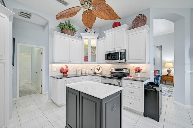 kitchen featuring appliances with stainless steel finishes, backsplash, white cabinetry, and a kitchen island