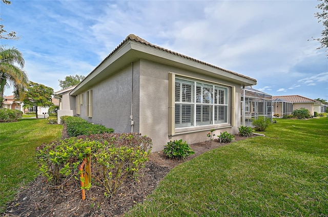 view of side of property featuring a yard and glass enclosure