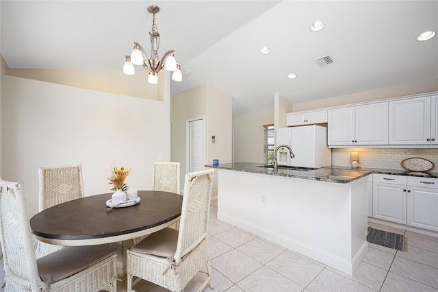 kitchen with sink, white cabinets, an island with sink, and a notable chandelier