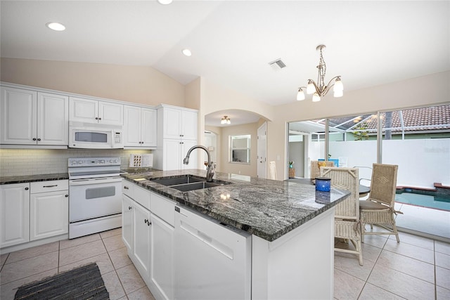 kitchen with white appliances, a kitchen island with sink, sink, white cabinets, and lofted ceiling