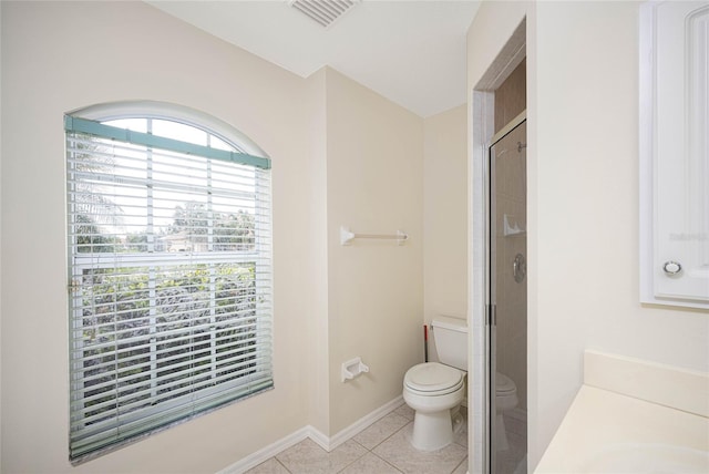 bathroom featuring tile patterned floors, toilet, and a shower with door