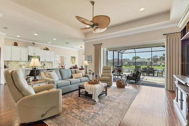 living room featuring hardwood / wood-style floors, ceiling fan, and crown molding