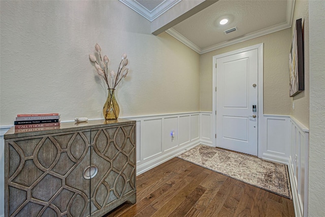 foyer featuring dark wood-type flooring, ornamental molding, and a textured ceiling