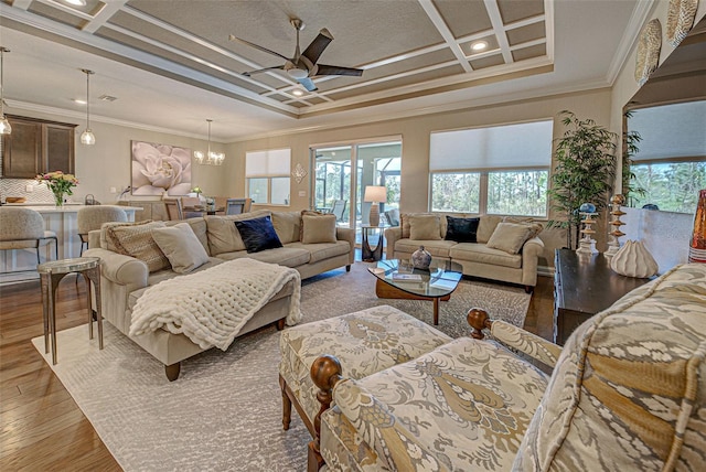 living room featuring ceiling fan with notable chandelier, beamed ceiling, ornamental molding, coffered ceiling, and light wood-type flooring