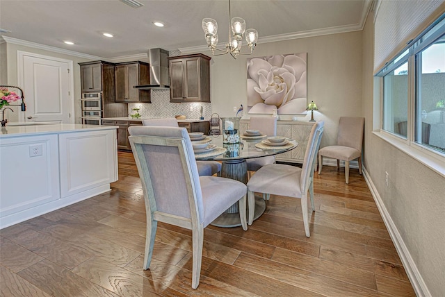 dining space with crown molding, sink, a notable chandelier, and light hardwood / wood-style flooring