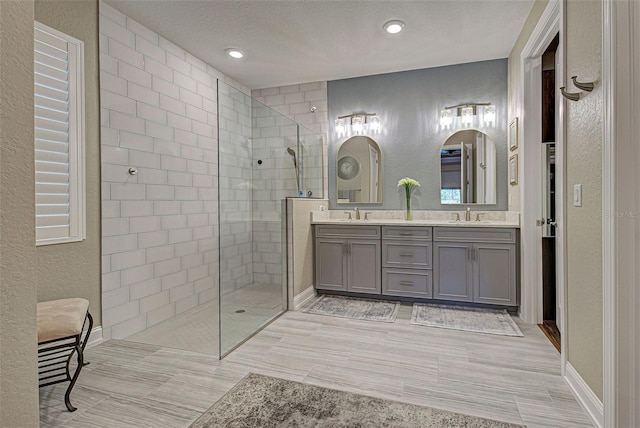 bathroom featuring vanity, a textured ceiling, and a tile shower