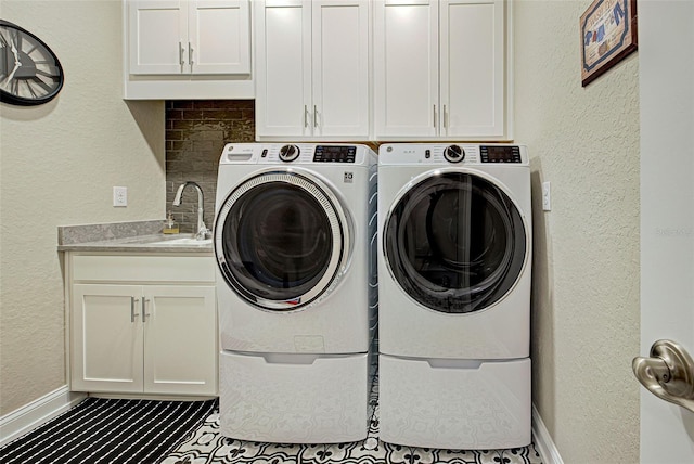 clothes washing area featuring cabinets, sink, and washing machine and clothes dryer