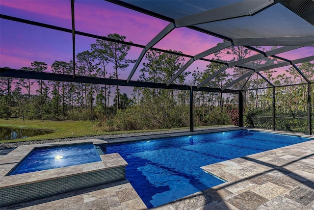 pool at dusk with an in ground hot tub, a patio area, and glass enclosure