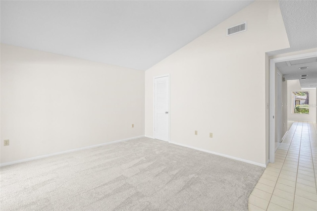 carpeted spare room with vaulted ceiling