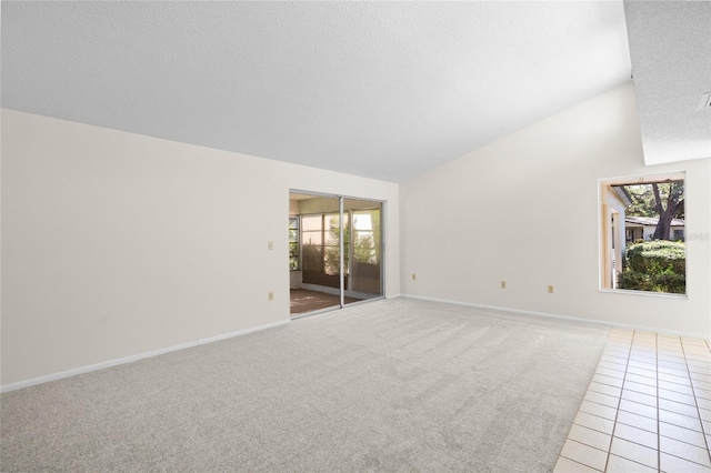 carpeted spare room featuring a healthy amount of sunlight, a textured ceiling, and vaulted ceiling