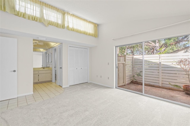 interior space with light carpet, ensuite bathroom, multiple closets, and sink