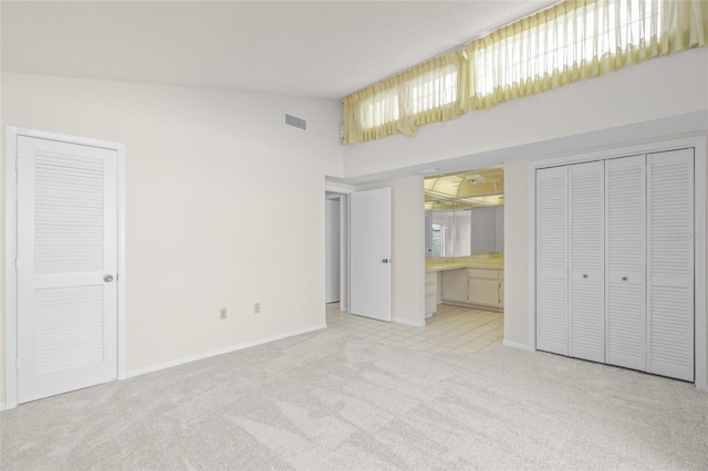 unfurnished bedroom featuring connected bathroom, high vaulted ceiling, and light colored carpet