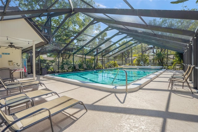 view of swimming pool featuring glass enclosure, ceiling fan, and a patio