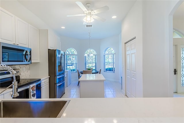 kitchen with hanging light fixtures, tasteful backsplash, white cabinets, light tile patterned flooring, and appliances with stainless steel finishes