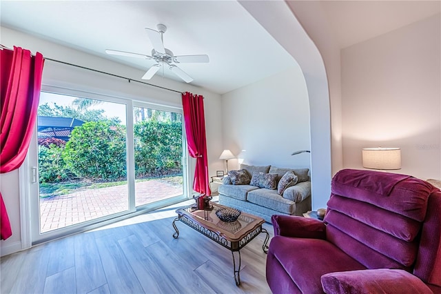 living room with ceiling fan, light hardwood / wood-style floors, and lofted ceiling