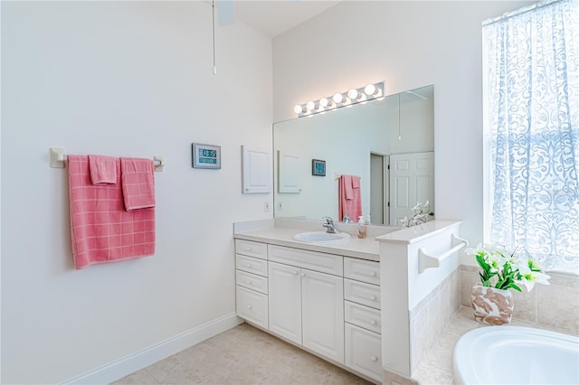 bathroom with tiled tub, tile patterned flooring, and vanity