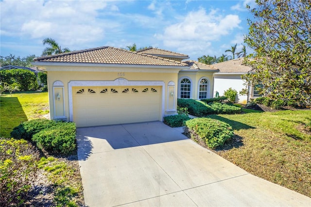 mediterranean / spanish-style home with a garage and a front lawn