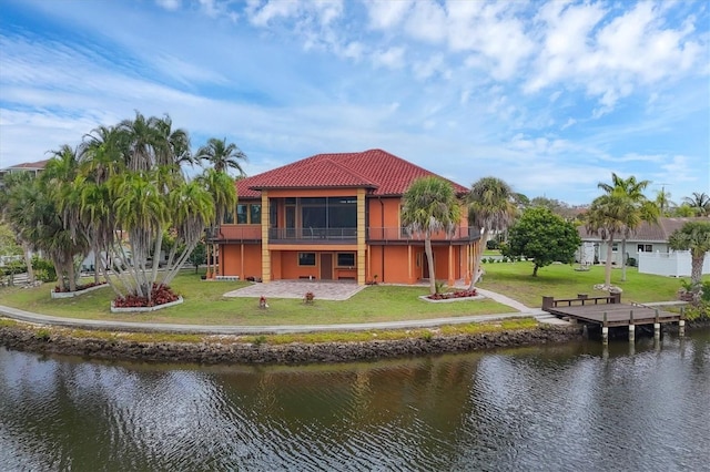 rear view of house featuring a lawn, a sunroom, and a water view