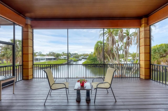 sunroom featuring a healthy amount of sunlight, a water view, and wooden ceiling