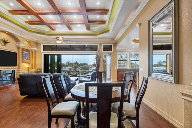 dining room with ceiling fan, dark wood-type flooring, coffered ceiling, beamed ceiling, and ornamental molding