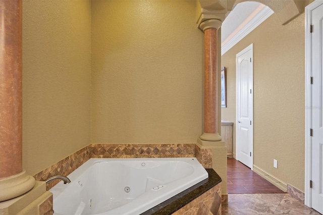 bathroom with decorative columns, hardwood / wood-style floors, and a relaxing tiled tub