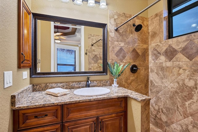 bathroom featuring a tile shower, vanity, and ceiling fan