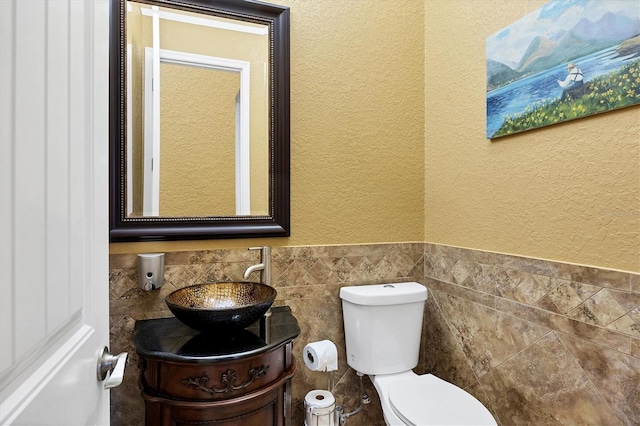 bathroom with vanity, toilet, and tile walls