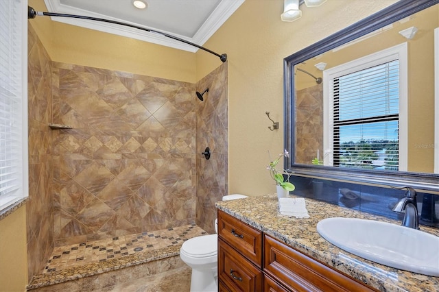 bathroom featuring vanity, toilet, crown molding, and a tile shower