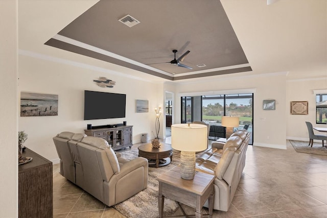 living room featuring a raised ceiling, ceiling fan, and ornamental molding