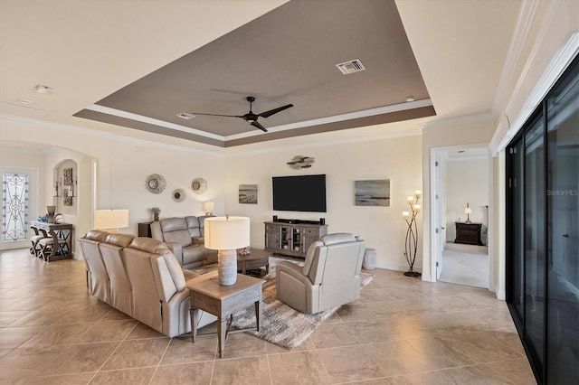 living room with a tray ceiling, crown molding, and ceiling fan