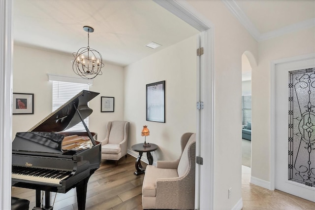 sitting room with a chandelier, light wood-type flooring, and ornamental molding