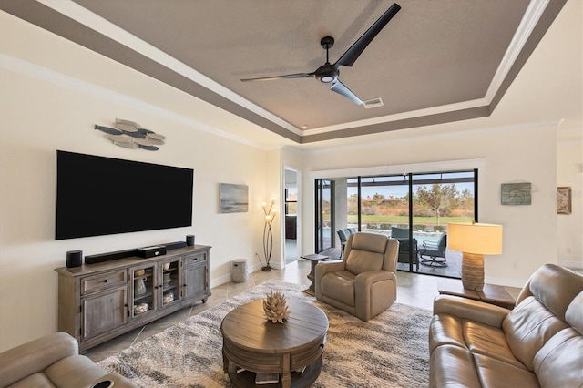 living room featuring a raised ceiling, ceiling fan, crown molding, and light tile patterned floors